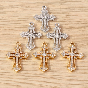 Detailed view of silver and gold rhinestone cross pendants for jewelry making on wood