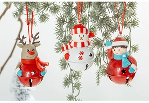 Detail of Christmas reindeer and snowman figurines on metal bells hanging from pine branch