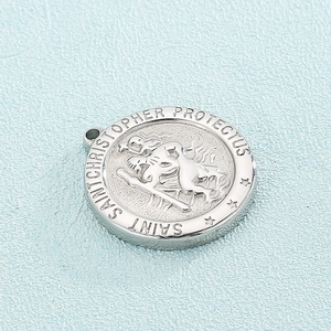 Detail of silver St. Christopher medal pendant with relief texture on blue background