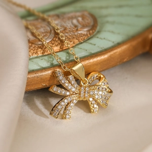Elegante goldene Schleifen-Halskette mit Zirkonia auf weichem Seidenhintergrund