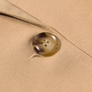 Dettaglio macro dei bottoni in resina tartarugata e del tessuto twill kaki sul cappotto
