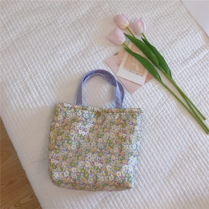 Close-up of floral tote bag showing daisy print, purple handle and gold snap button closure
