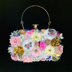 Close-up of 3D sequin flowers and gold metal handle on a luxury evening clutch bag