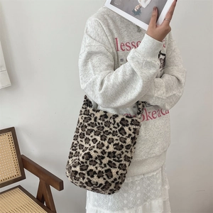 Close-up of leopard print plush tote bag held by a model in a minimalist setting