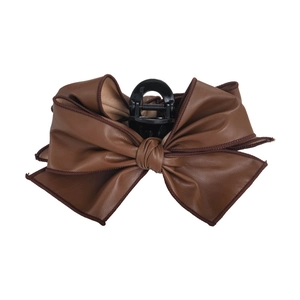 Brown faux leather bow claw clip with black piping on white background