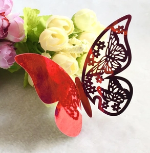 Detail of 3D hollow butterfly cake topper in metallic red placed on soft flower petals