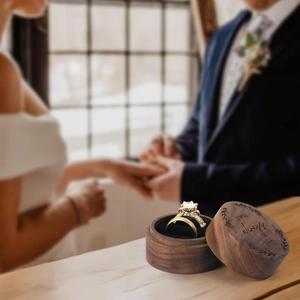 Close-up of heart walnut wood ring box with it was always you engraving at a wedding