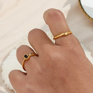 Detailed view of two gold bamboo-style rings with one black gemstone and twisted pattern