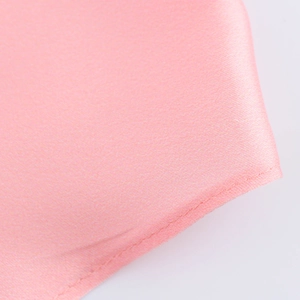 Gros plan détaillé sur la texture du satin rose et les coutures du chemisier femme