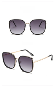 Detail of oversized square sunglasses with black frames and gold metal temples