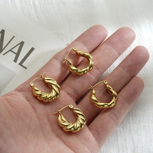 Close-up of gold twisted hoop earrings held by hand showing real size and texture