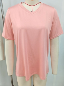 Dettaglio della trama del tessuto e del collo a V della t-shirt rosa su un manichino