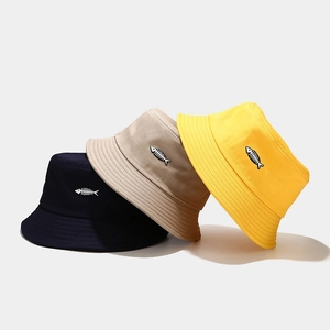 Three cotton bucket hats in blue, beige, and yellow with fishbone embroidery detail
