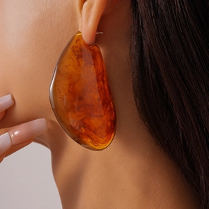 Gros plan d'un mannequin portant de grandes boucles d'oreilles ambrées en résine écaille