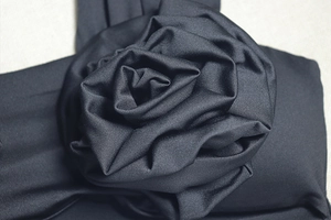 Détail en gros plan d'une rose 3D noire sur une robe de soirée en maille ajustée
