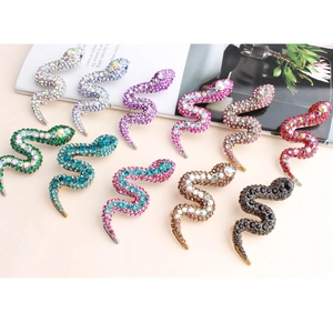 Flat lay of colorful crystal snake brooches in green pink and blue with rhinestone details
