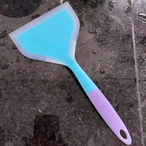 Wide silicone spatula for tamagoyaki with blue head and purple handle on stone surface