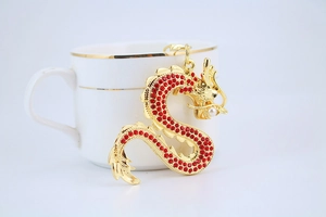 Détail d'un porte-clés dragon doré avec strass rouges et une perle dans sa bouche