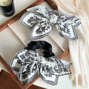 Detail of premium black and white paisley bow scrunchies on a wooden tray decor