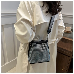 Détail d'un sac seau noir avec strass argentés et une large bandoulière à rayures