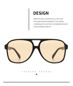 Detail of aviator sunglasses featuring a thick black frame and amber lenses with double bridge