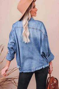 Detail of blue denim shirt showing distressed fringe hem and vintage washed texture
