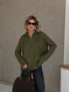 Detail of metal half-zip closure and ribbed knit texture on olive green sweater