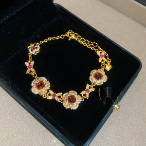 Macro shot of gold-plated floral bracelet with red gemstone in black jewelry box