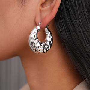 Macro shot of silver hammered texture hoop earrings featuring organic geometric curves