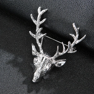 Macro view of silver reindeer head brooch with detailed antlers on black leather texture