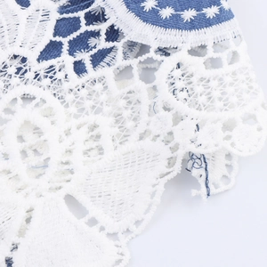 Elegant white lace embroidery on blue denim jacket with sophisticated floral cutouts