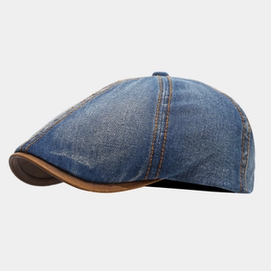 Detail of vintage denim newsboy cap with brown leather brim and contrast orange stitching