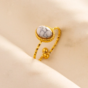 Detail of adjustable gold ring featuring white marble stone and diamond-cut textured band