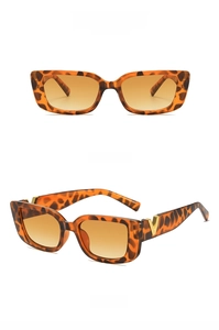 Detail of tortoise shell sunglasses with orange gradient lenses and gold V-shaped accents