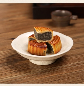 Detail of sliced Chinese mooncakes on a white crackle-glaze ceramic pedestal tray