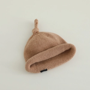 Texture de maille d'un bonnet bébé marron avec nœud supérieur et bordure roulée