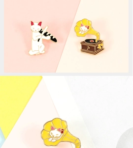 Close-up of cat-themed enamel pins featuring a white cat and a vintage gramophone
