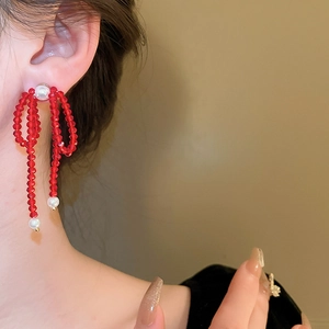 Elegant red crystal bow earrings with pearls shown on model in a stylish close-up shot