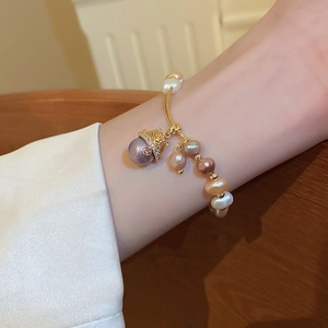 Detail of freshwater pearl bracelet on wrist with golden Maneki Neko cat charm and zircons