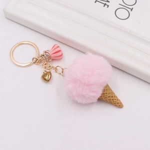 Detail of plush ice cream keychain with pink fur ball, golden heart charm and tassel