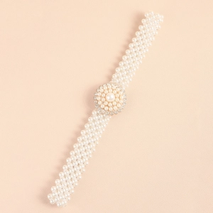 Detailed close-up of woven pearl belt featuring a circular diamond-encrusted buckle