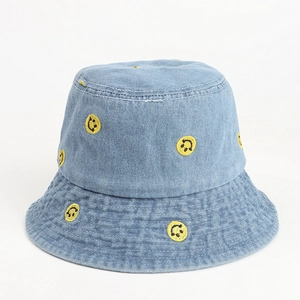 Detailed close-up of yellow smiley face embroidery on blue denim bucket hat with stitching