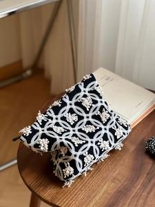 Détail de la broderie d'anémone et de dentelle florale sur le sac en toile noire