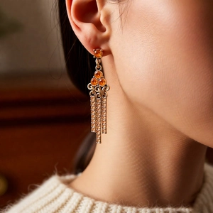 Close-up of vintage gold triangle tassel earrings with amber gems on female model