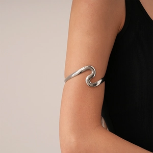 Polished silver wavy geometric upper arm cuff featuring a sleek minimalist metal design