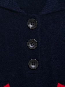 Detail of dark navy knit fabric showing black buttons and contrasting red accent trim