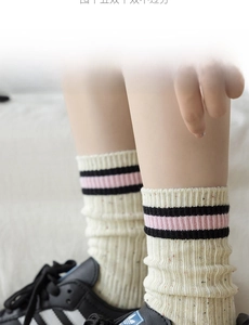 Dettaglio calzini color crema con strisce nere e rosa e trama a macchie colorate
