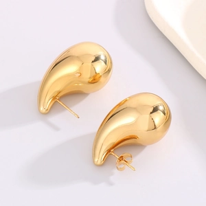 Macro shot of mirror-polished gold teardrop earrings with smooth metallic finish