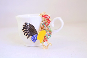 Detail of colorful enamel rooster keychain with crystals on a golden metal base