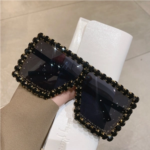 Close-up of oversized square sunglasses featuring hand-set black crystal-embellished frames